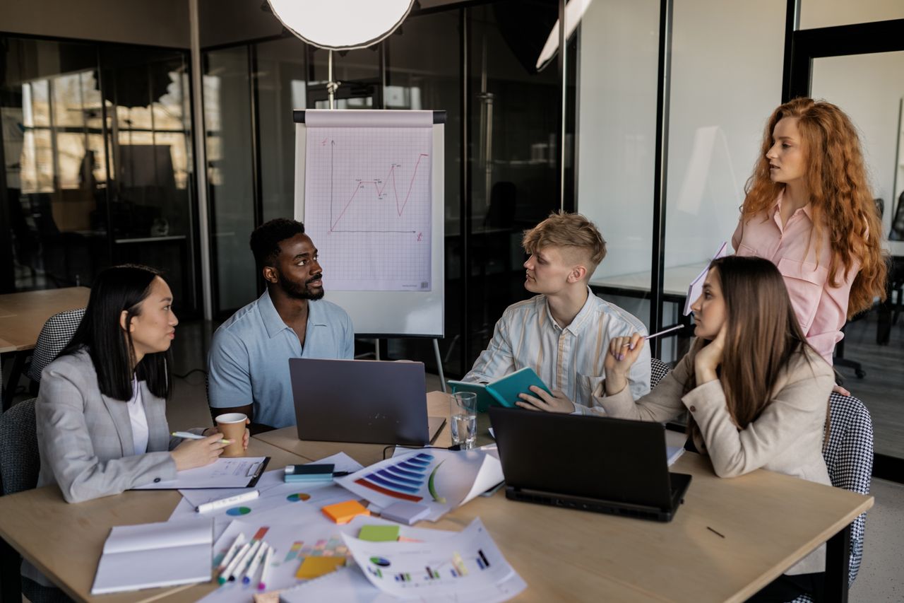 A diverse team discussing business strategy around a conference table in a modern office.